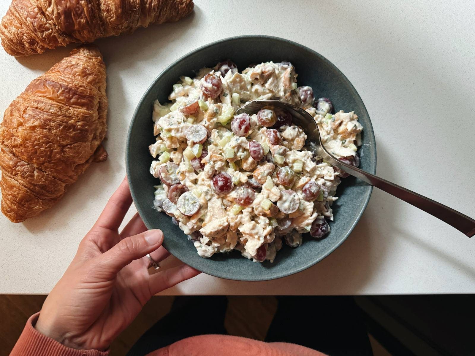 Chicken salad in a bowl with croissants on the side.