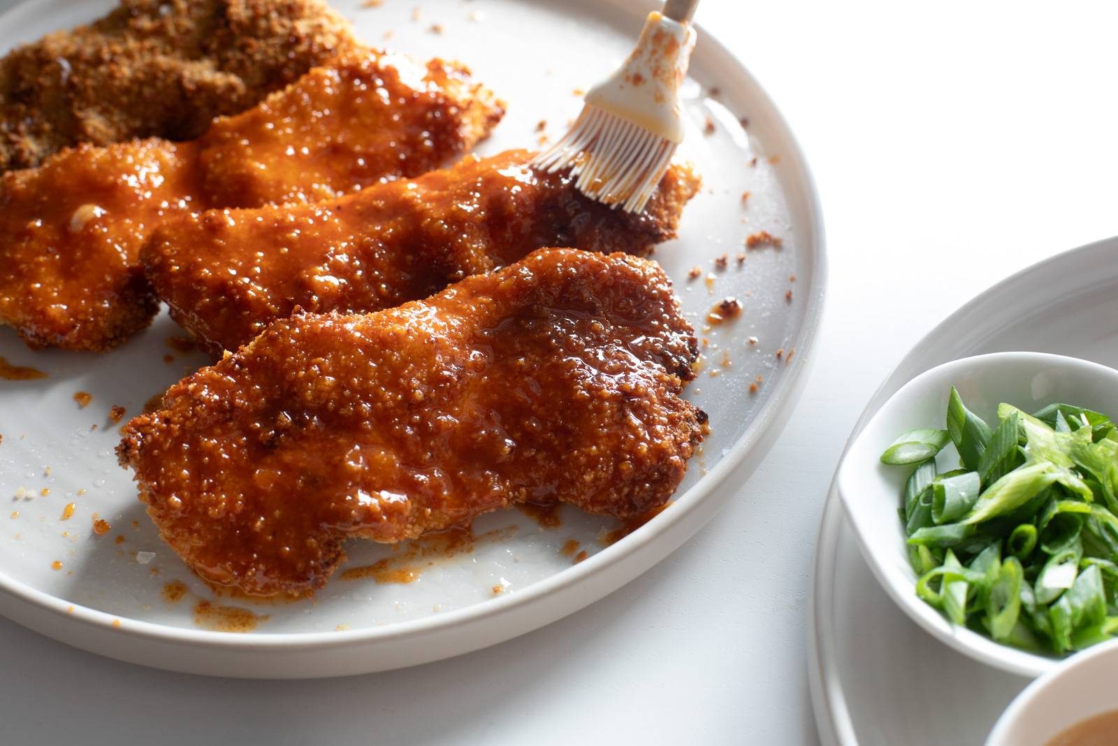 Brushing butter on chicken on a plate.