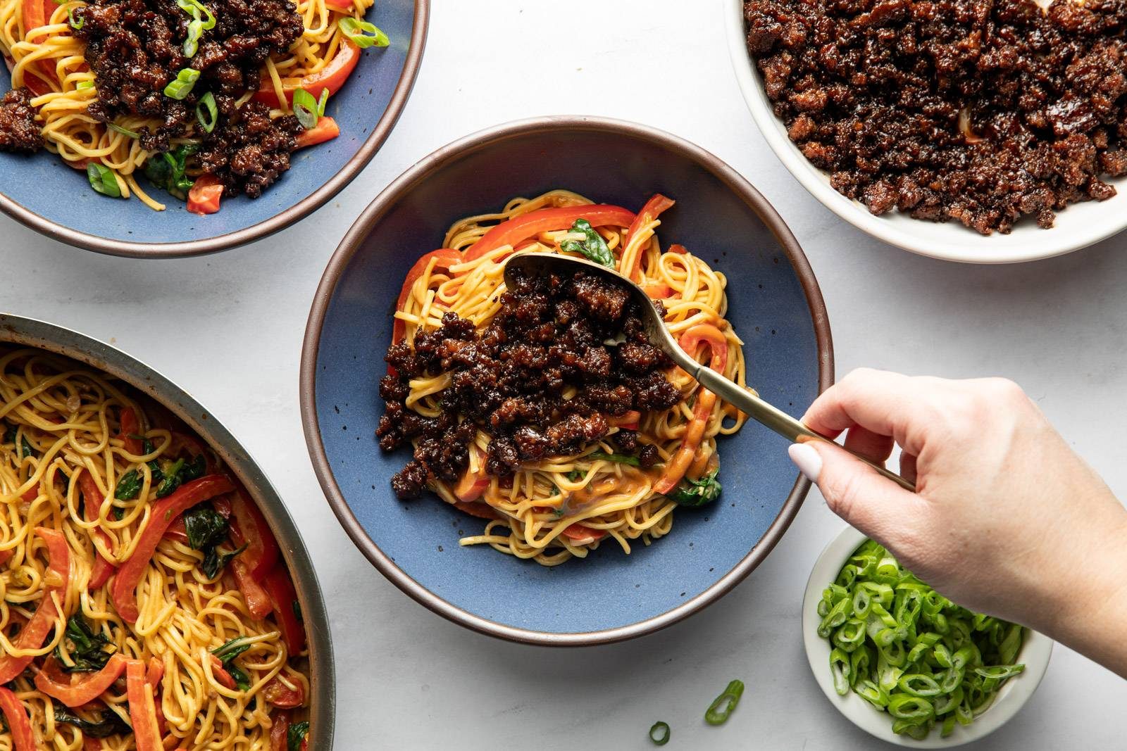 Adding beef to a bowl of peanut noodles.