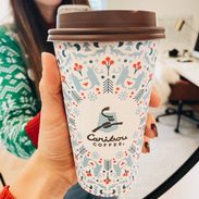 White woman holding holiday themed coffee cup.