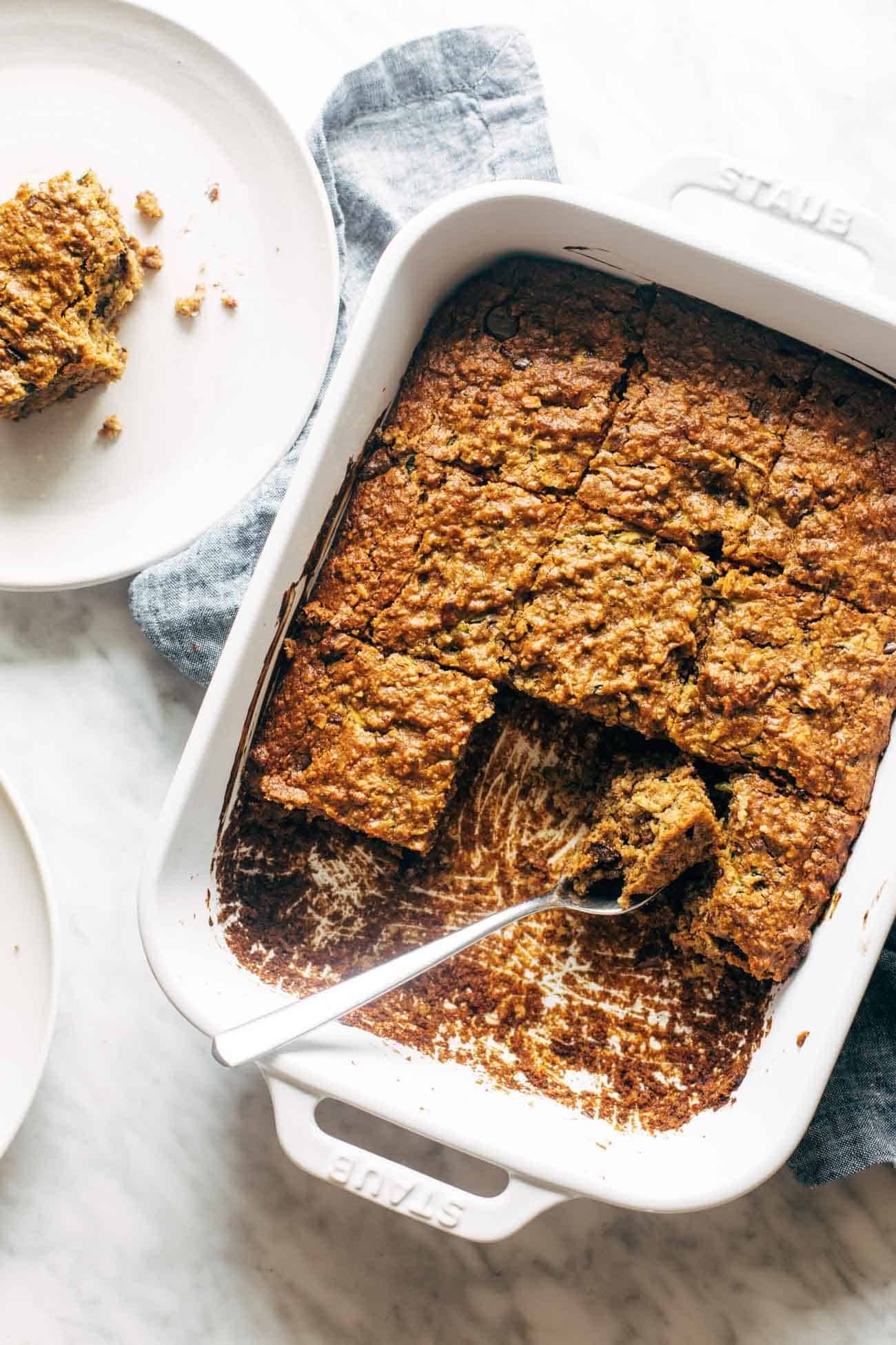 Overhead image of almond butter chocolate chip zucchini bars with a few bars taken out of the pan and a fork in the pan.