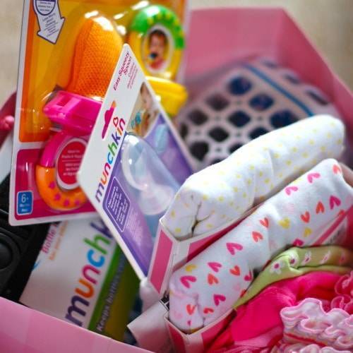 Gifts for a baby shower in a pink gift bag.
