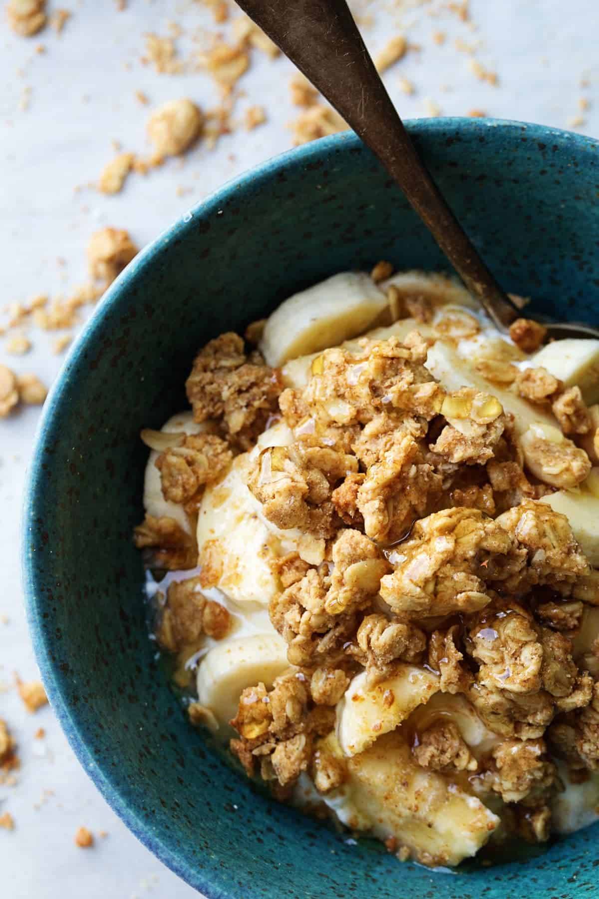 Granola over bananas in a blue bowl.