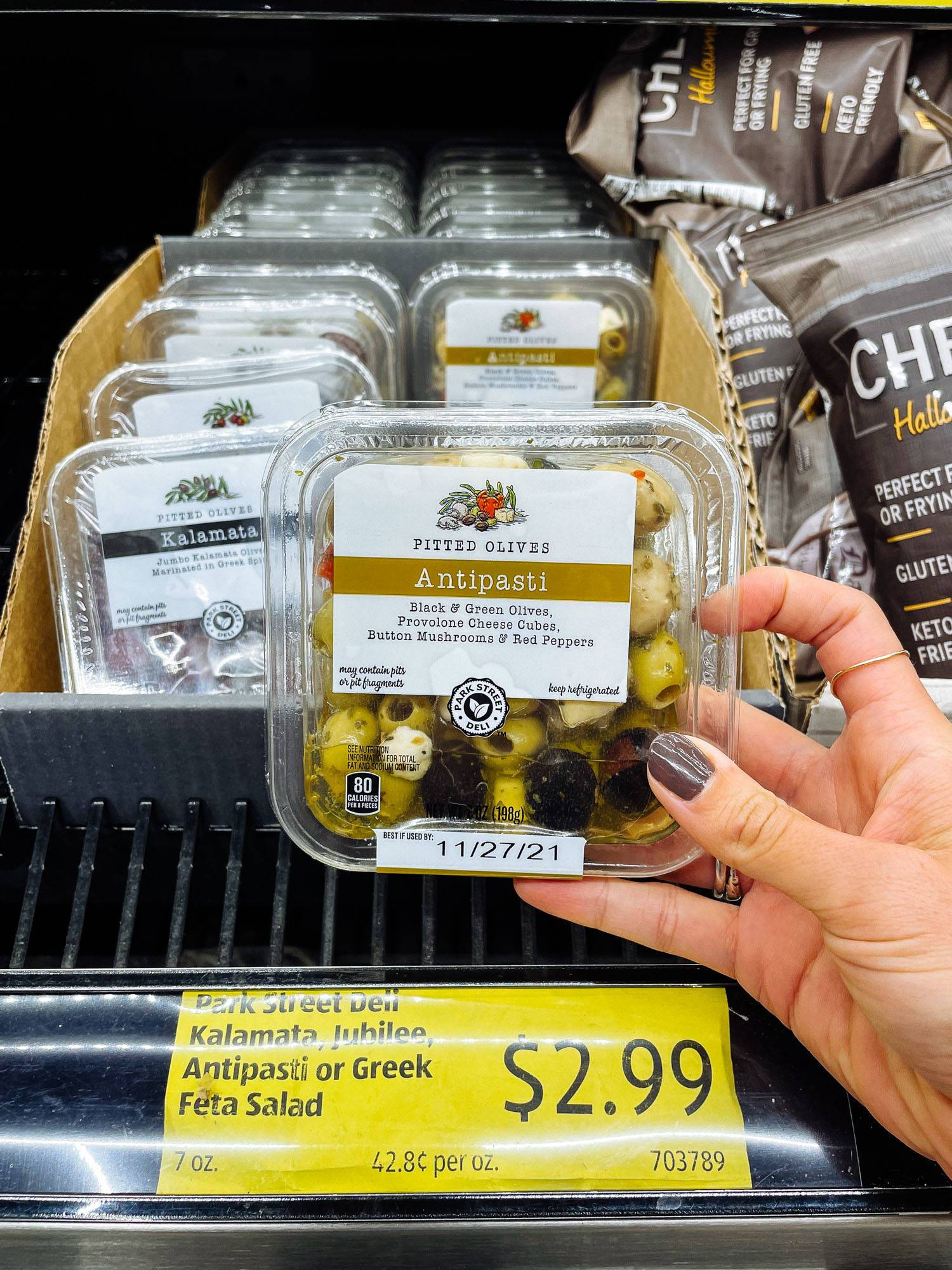 White hand holding antipasti olives and cheese container from ALDI.