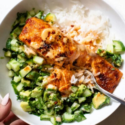 Bang bang salmon in a bowl with rice and cucumber salsa.