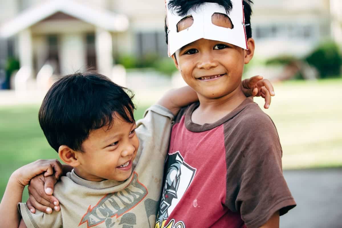 Young boys hugging and looking at camera.