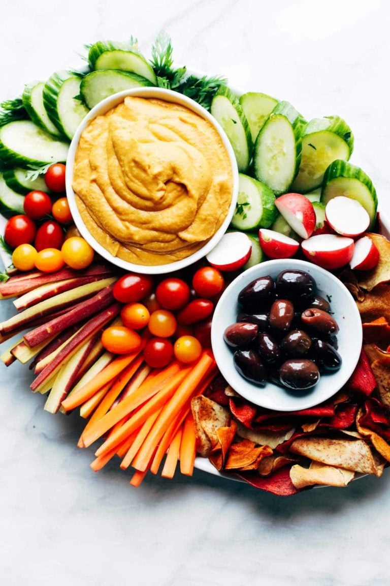 Curry hummus on a plate with veggies and olives.