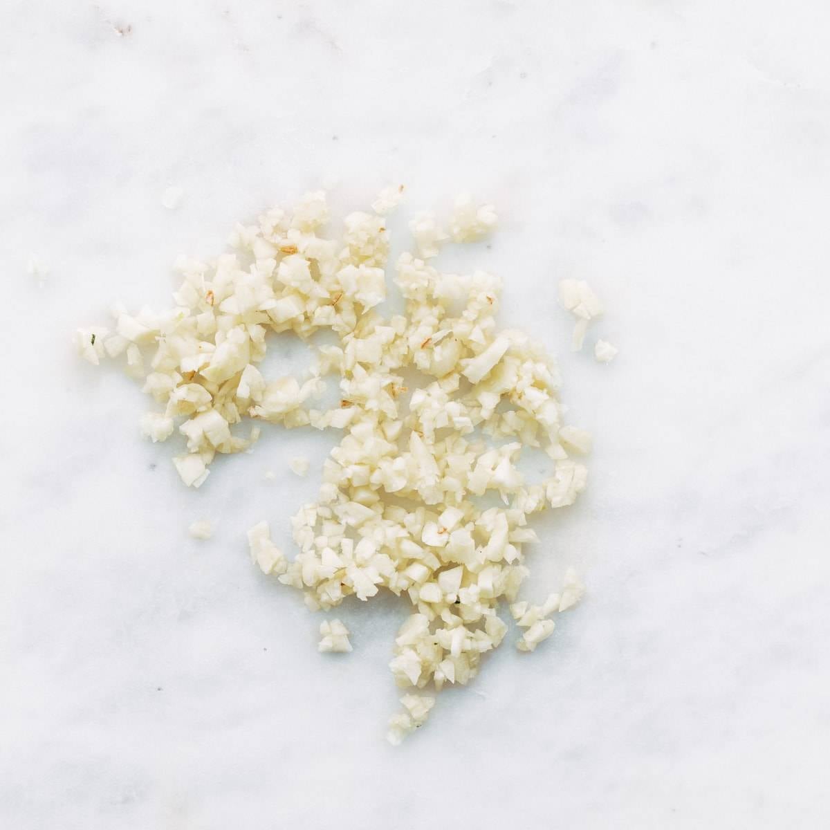Pieces of minced garlic on a white surface.