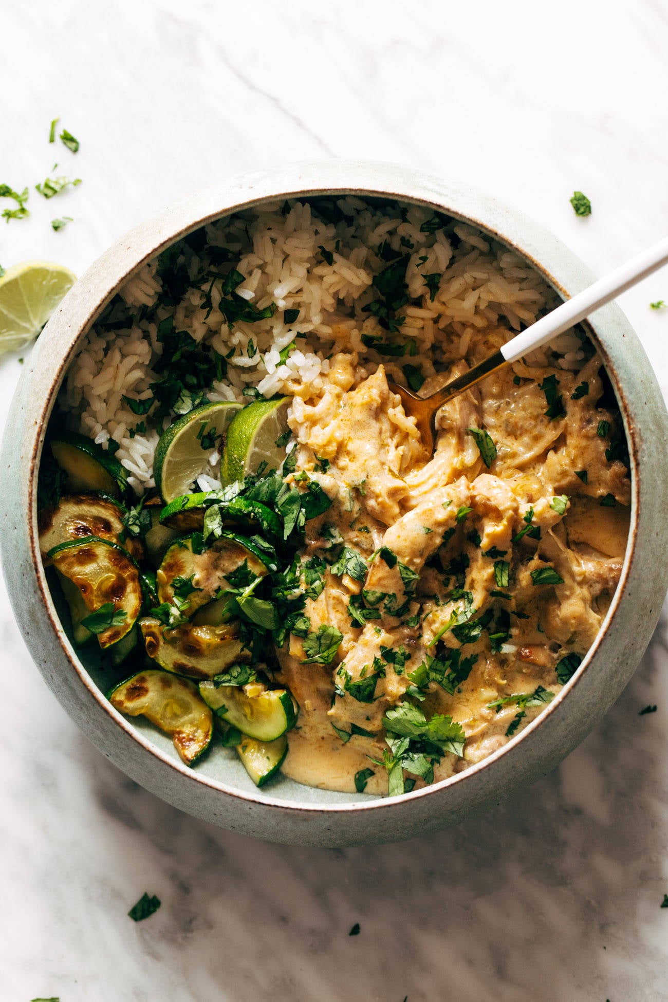 Lemongrass chicken in a bowl with rice and zucchini and topped with fresh herbs.